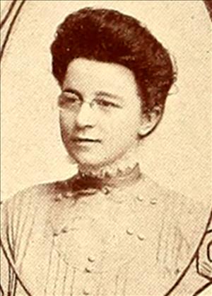 A yearbook portrait of a woman with glasses and long hair in an up do. 